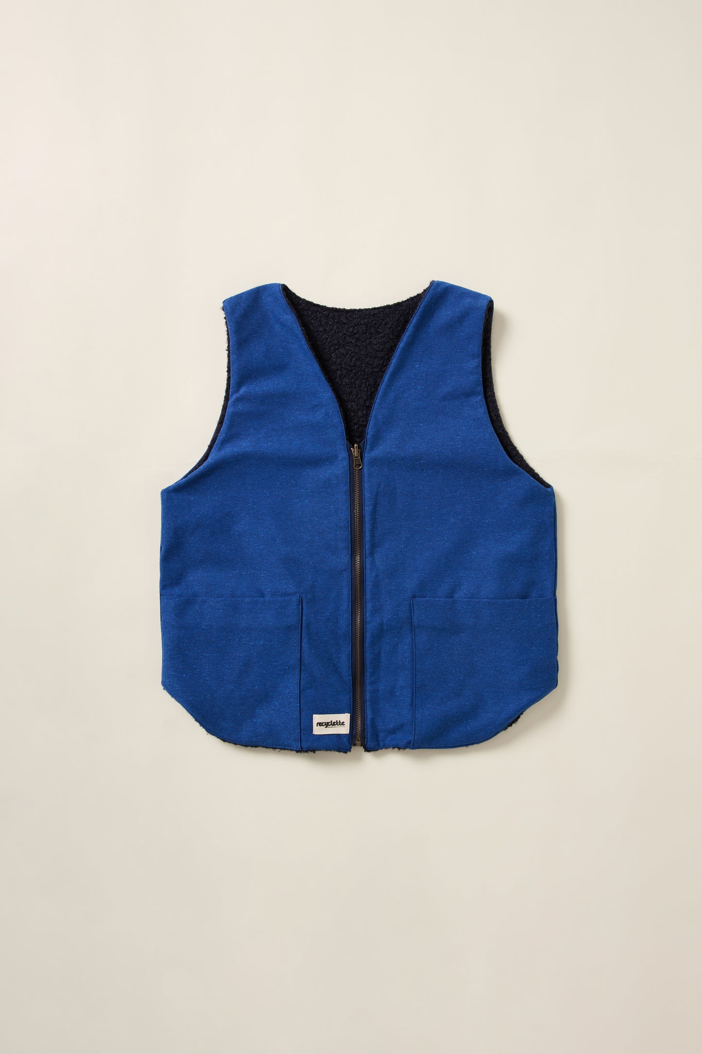 Gilet réversible, bleu denim d'un coté et et moumoute bleu de l'autre. Gilet en aplat.