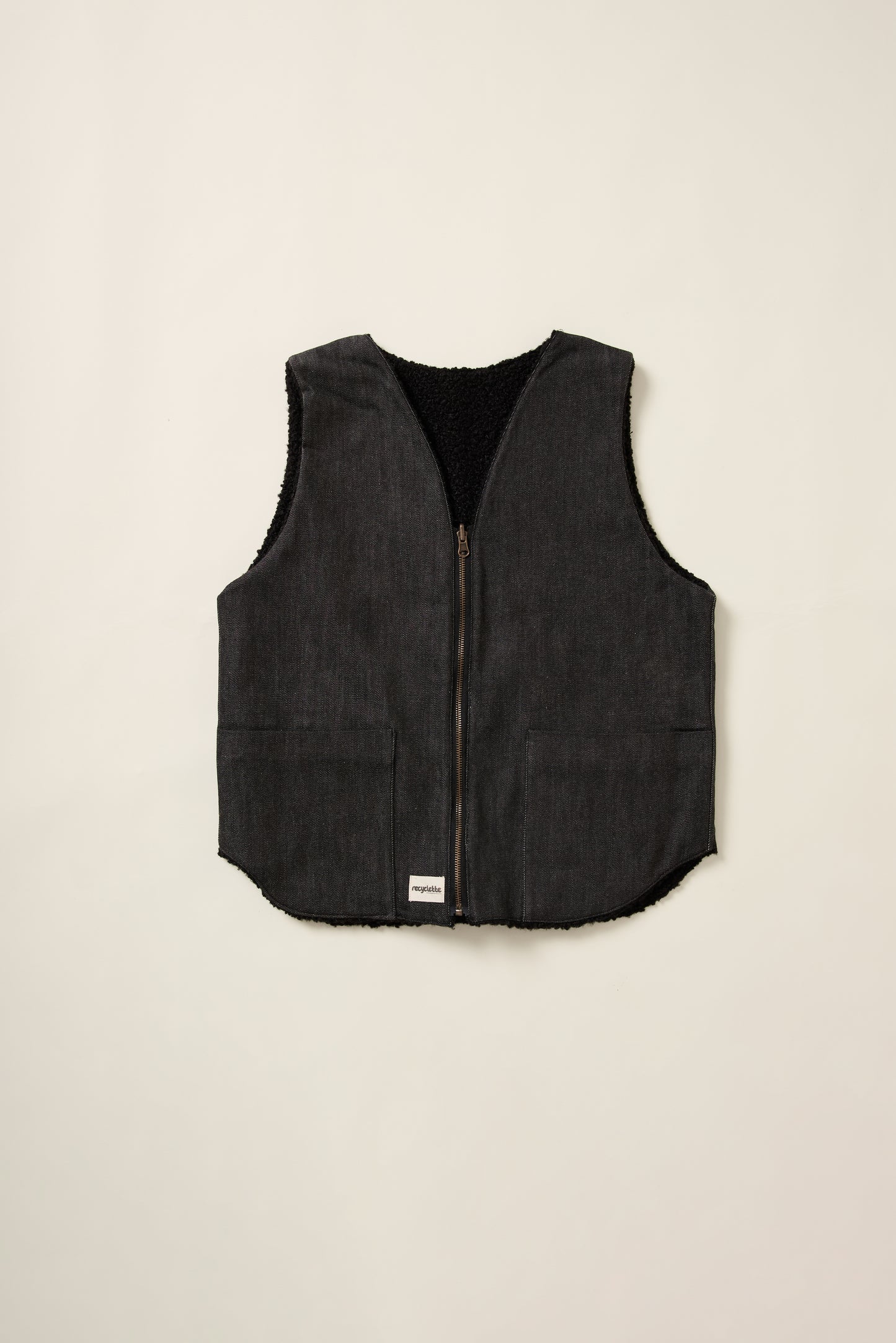 Gilet réversible, coté denim noir, sans manche, en aplat.
