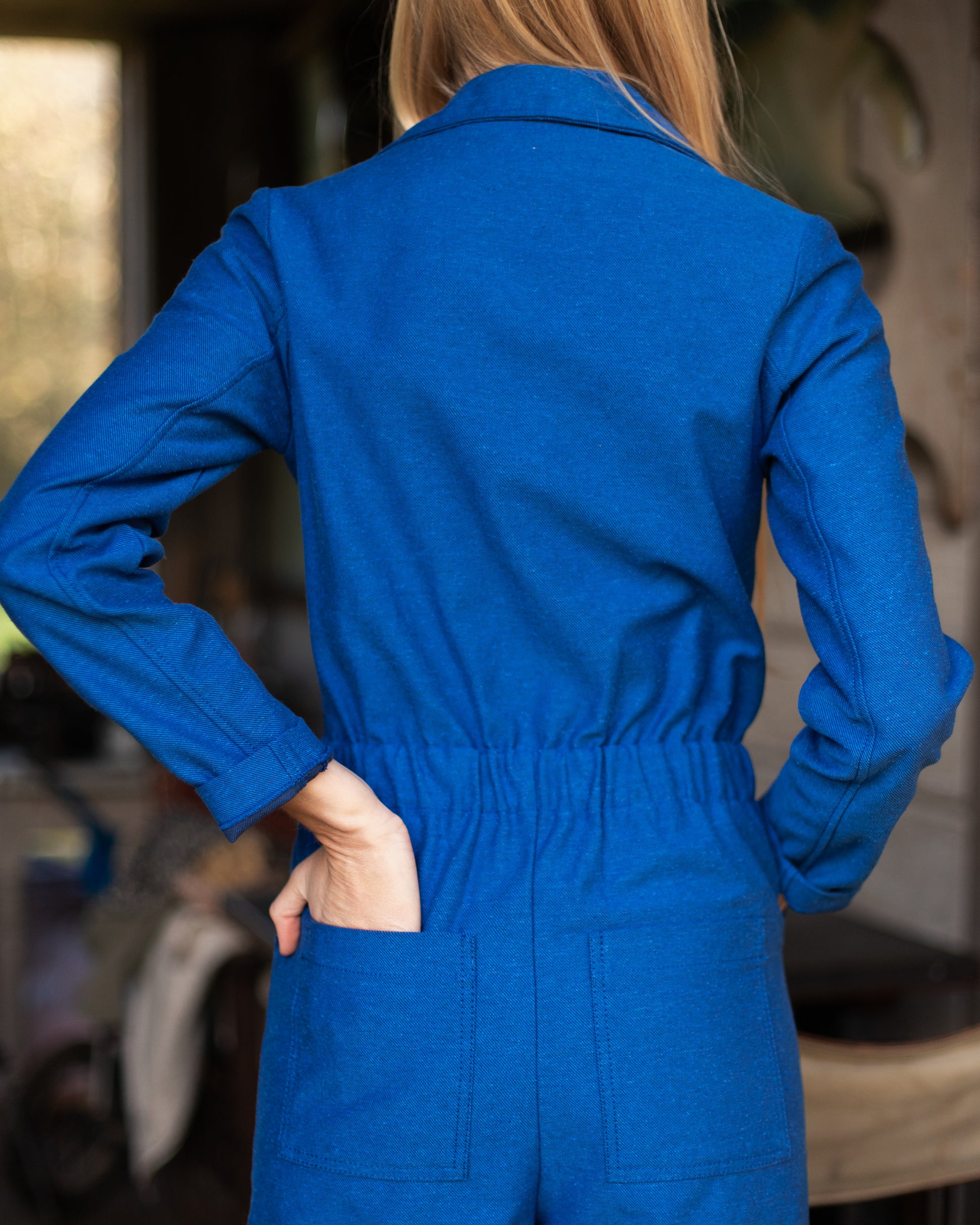 Femme portant une combinaison de travail bleue en tissu upcyclé, style vintage et coupe moderne.