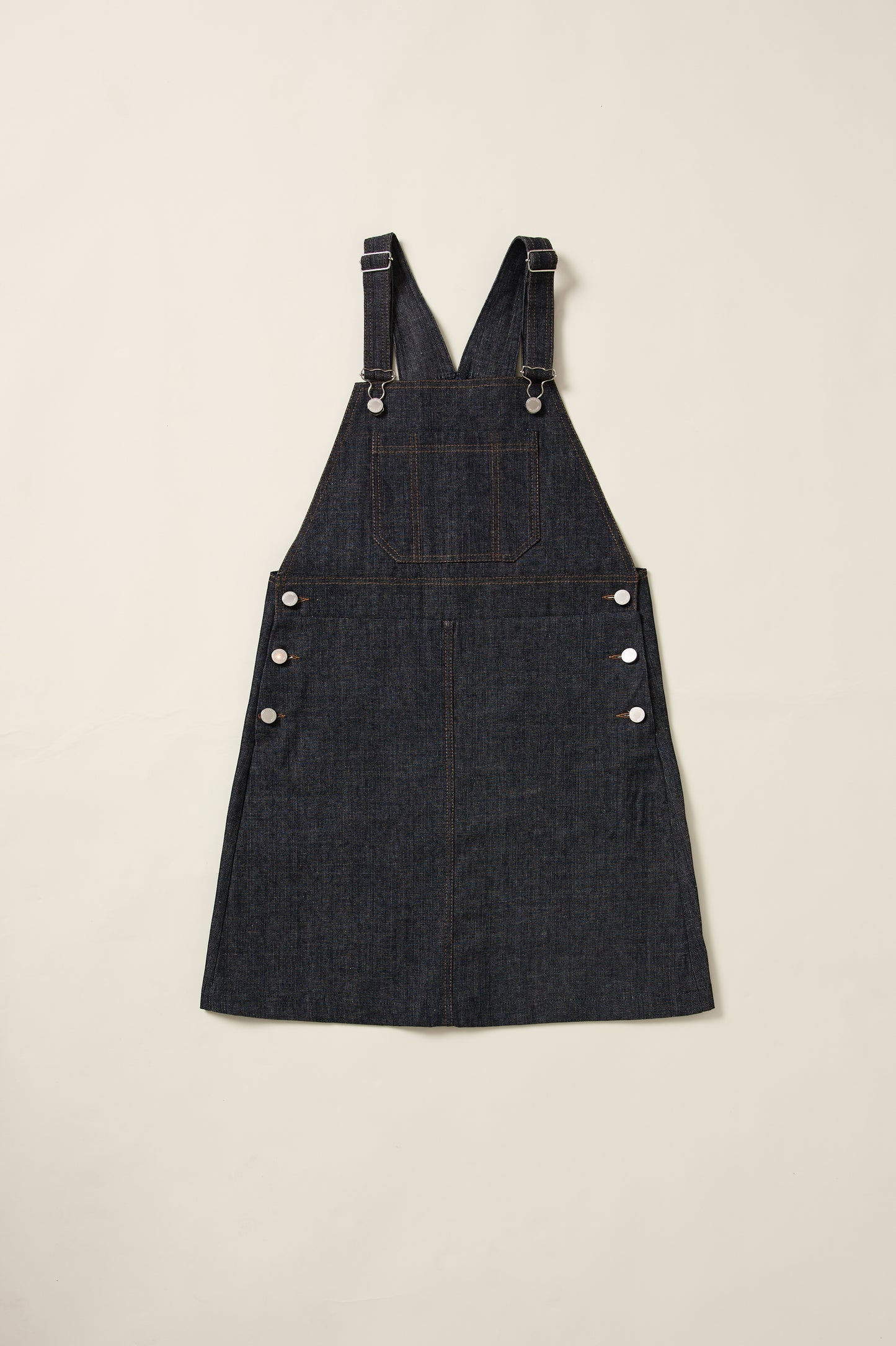 Aplat de la robe salopette en denim Recyclette, avec sa grande poche sur le devant et ses bretelles réglabes.