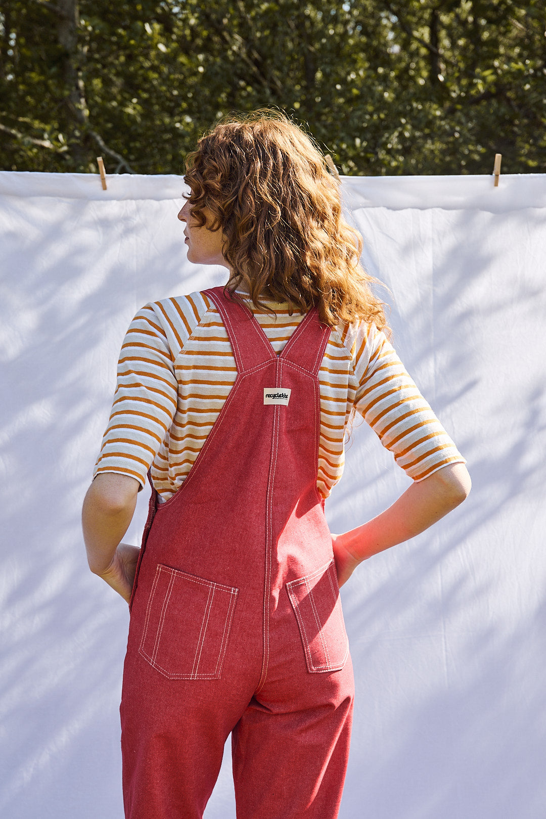 Salopette en denim rouge modèle Dancing Queen portée par une mannequin, associée à une blouse blanche.