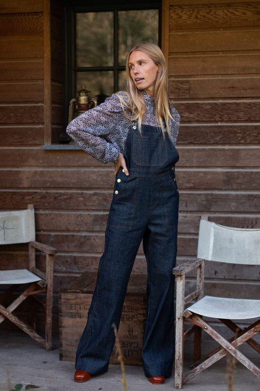 La salopette en denim brut, en modèle dancing queen, portée avec une blouse à fleurs.