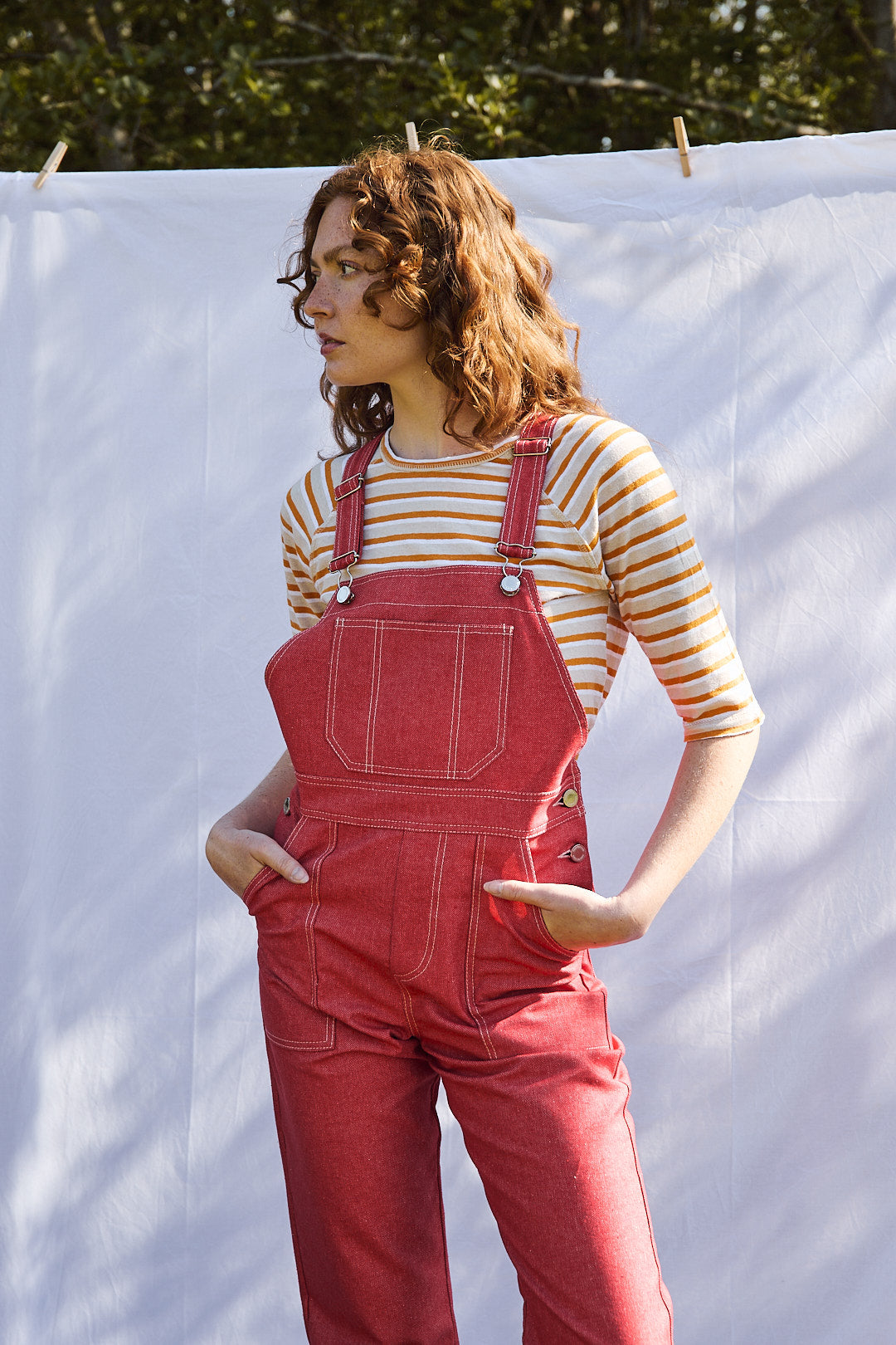 Salopette en denim rouge modèle Fernandi portée par une mannequin, associée à une pull à manches courtes à rayure rouge.