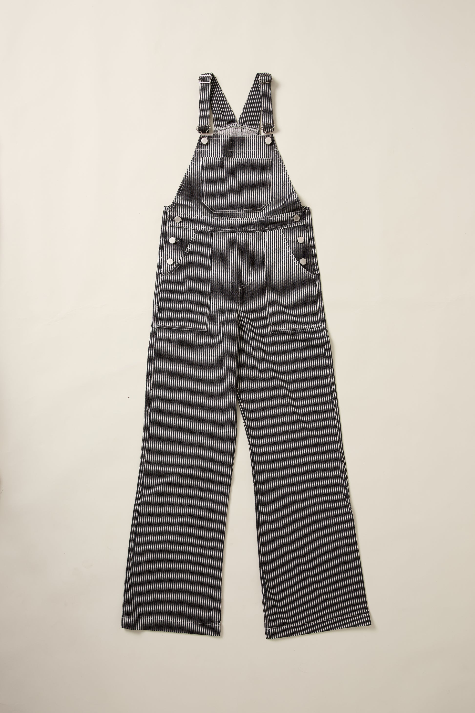 Une salopette en denim rayée bleu et blanche, en aplat.