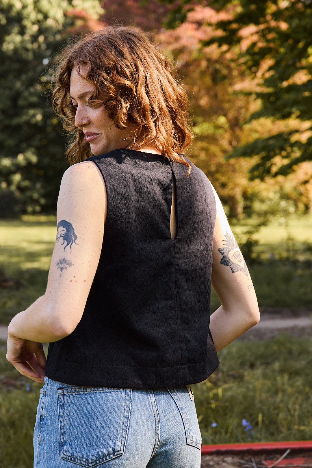 Mannequin portant le top noir avec un jean bleu taille haute et des petites chaussures noires. Look chic Recyclette.