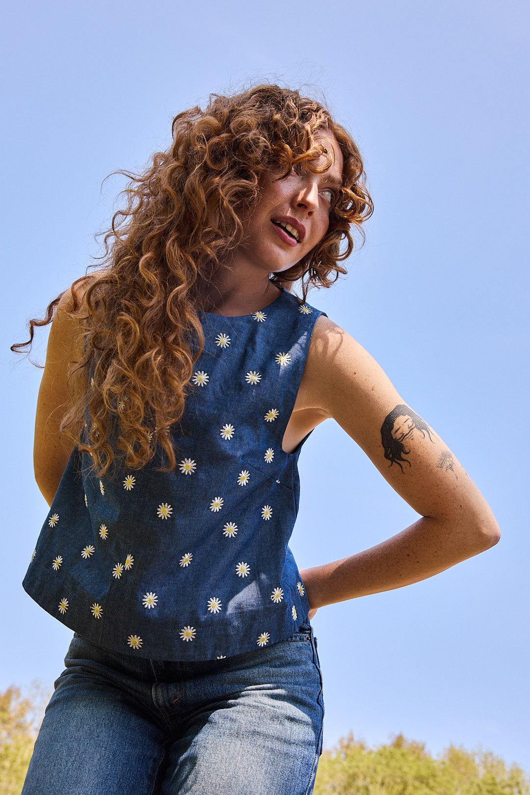 Mannequin portant le top brodé Recyclette avec un jean bleu assorti, créant un look estival.
