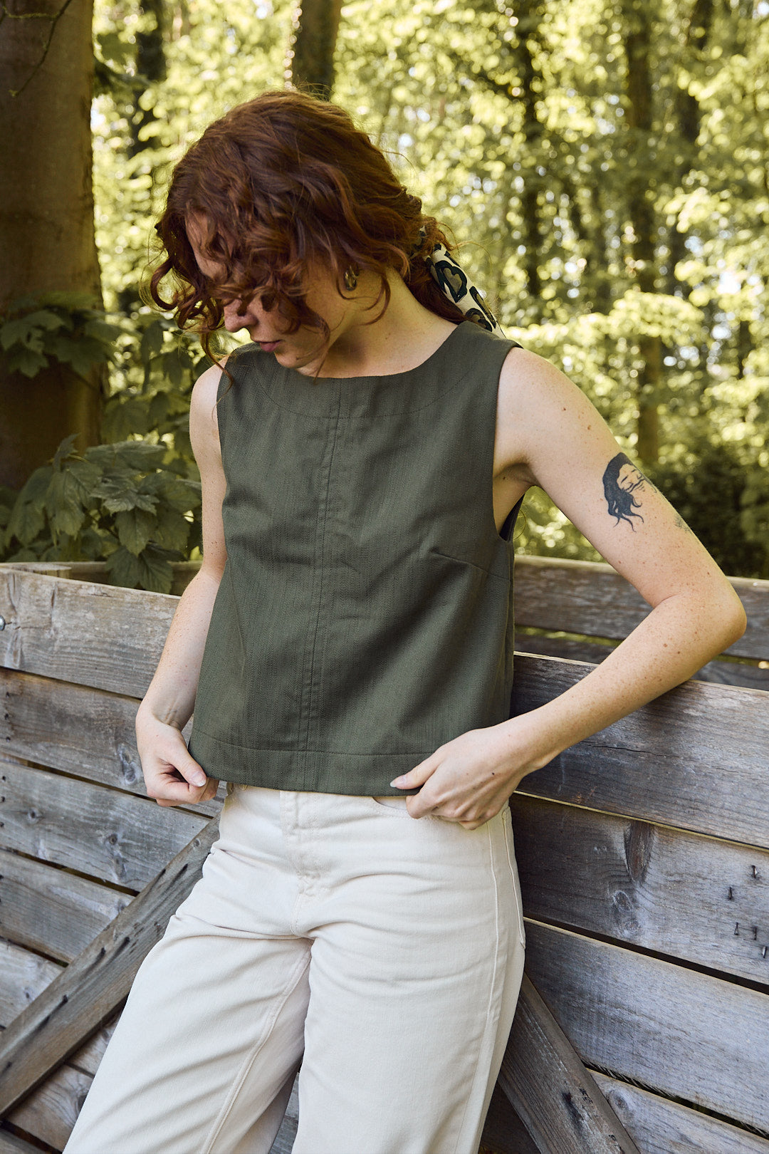 Mannequin portant le top kaki avec un pantalon écru, style sobre Recyclette. Un top chasuble, qui suit les tendances 2025.