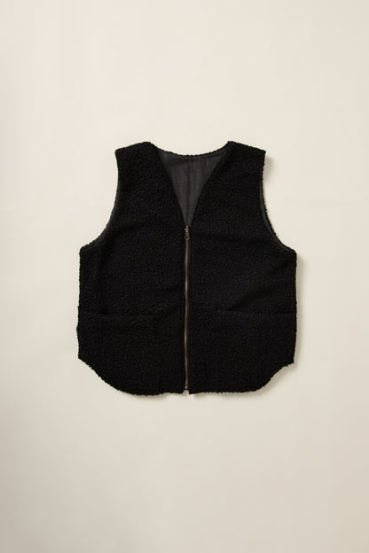 Gilet réversible, sans manche, coté moumoute noir, en aplat.
