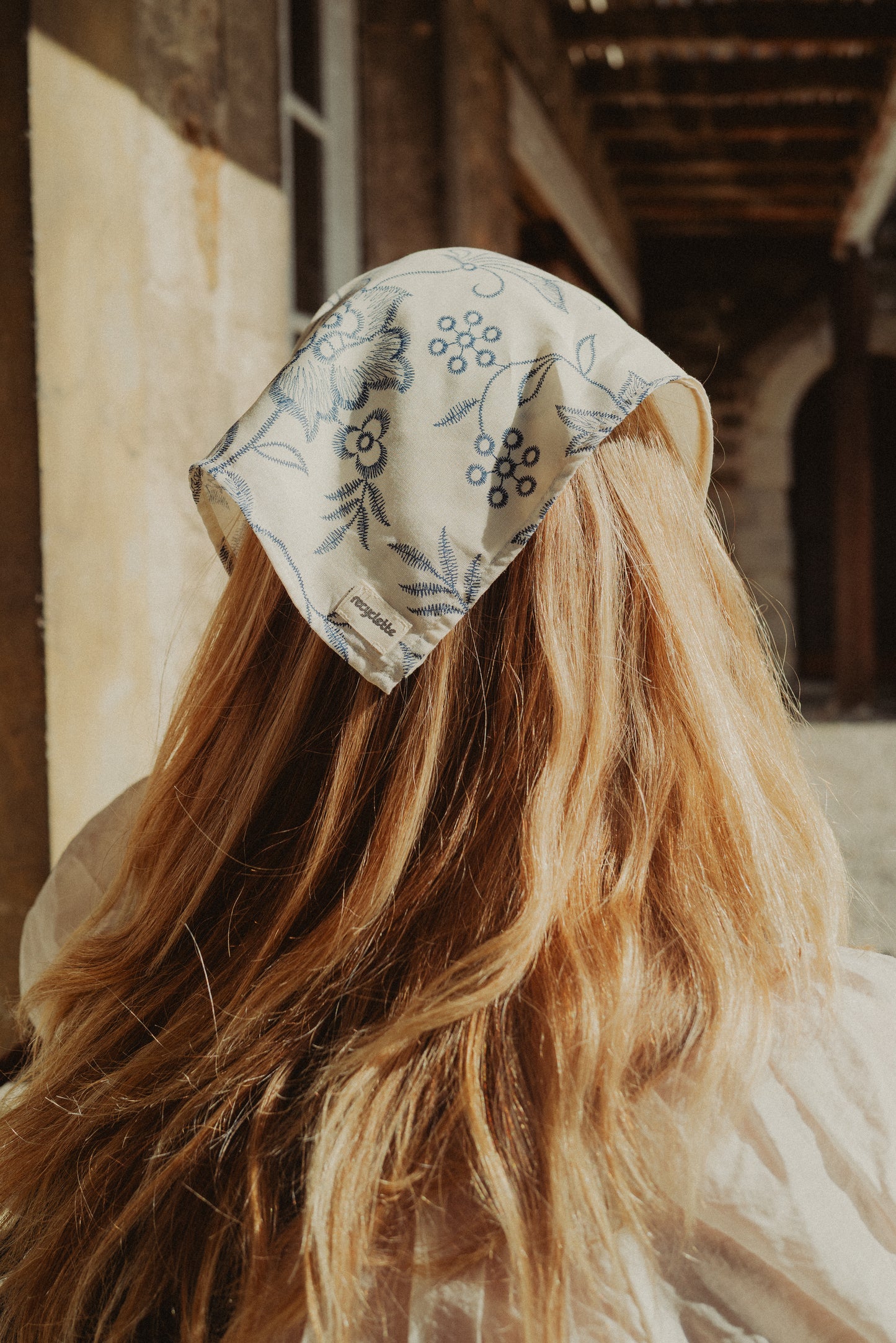 Foulard blanc fleuri porté dans les cheveux 