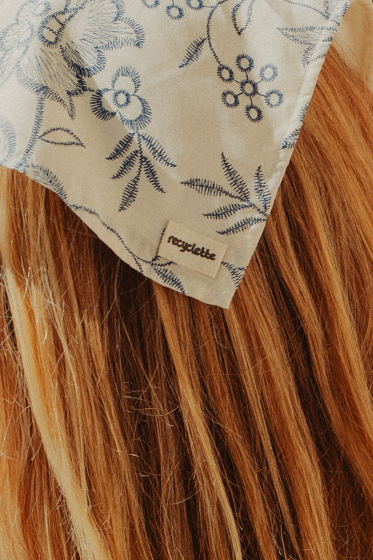 Foulard blanc fleuri bleu porté dans les cheveux 