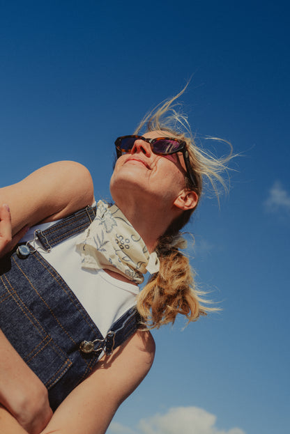 Foulard blanc fleuri porté autour du cou avec une salopette en denim brut