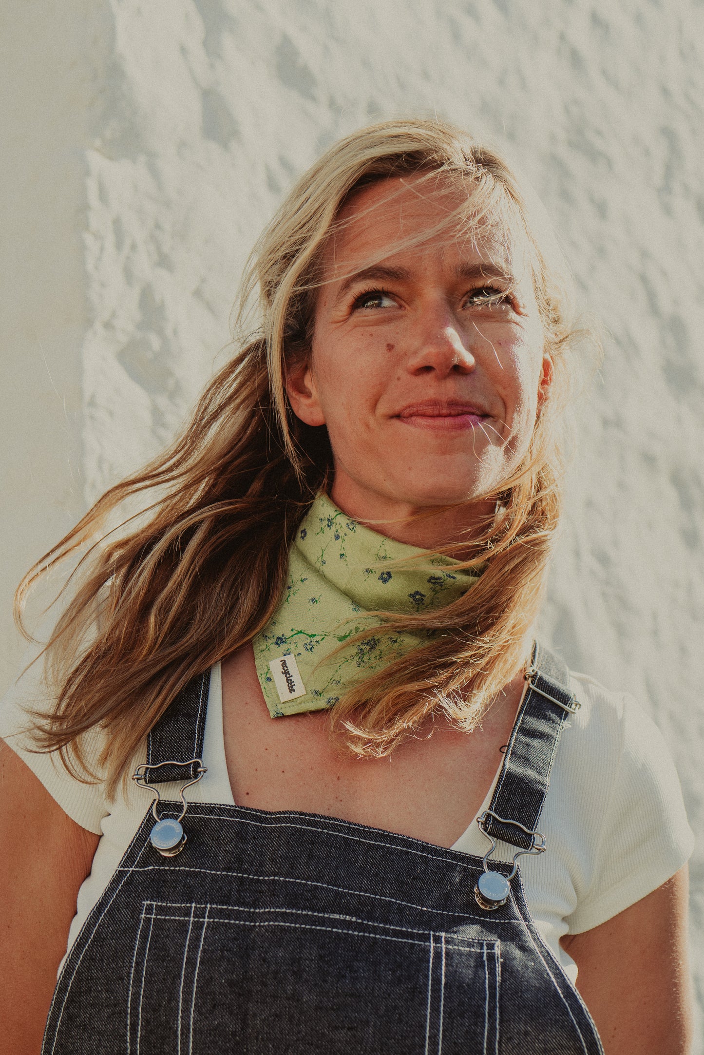 foulard vert fleuri porté au cou avec une salopette coupe grise en denim 