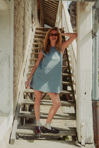 Robe sans manches en denim portée avec des lunettes de soleil et des mocassins