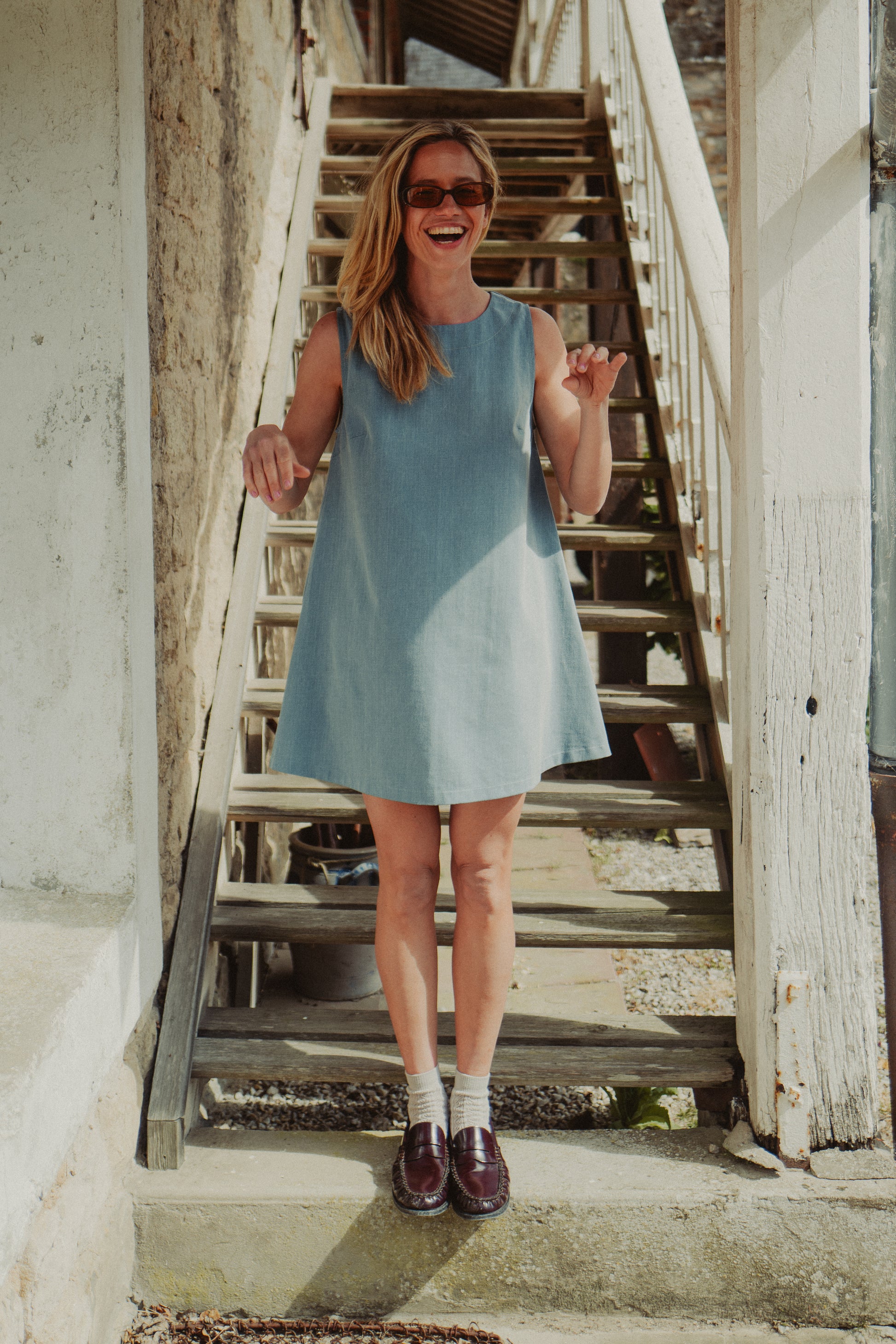 mannequin qui sourit avec une robe en denim clair et des mocassins