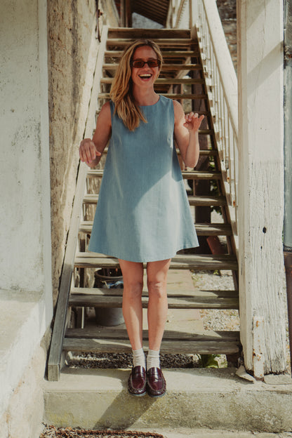 mannequin qui sourit avec une robe en denim clair et des mocassins