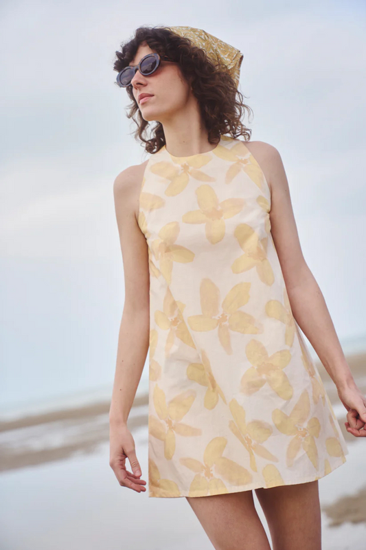 Notre robe courte jaune, avec des fleurs accompagnée de notre foulard soleil jaune dans les cheveux.