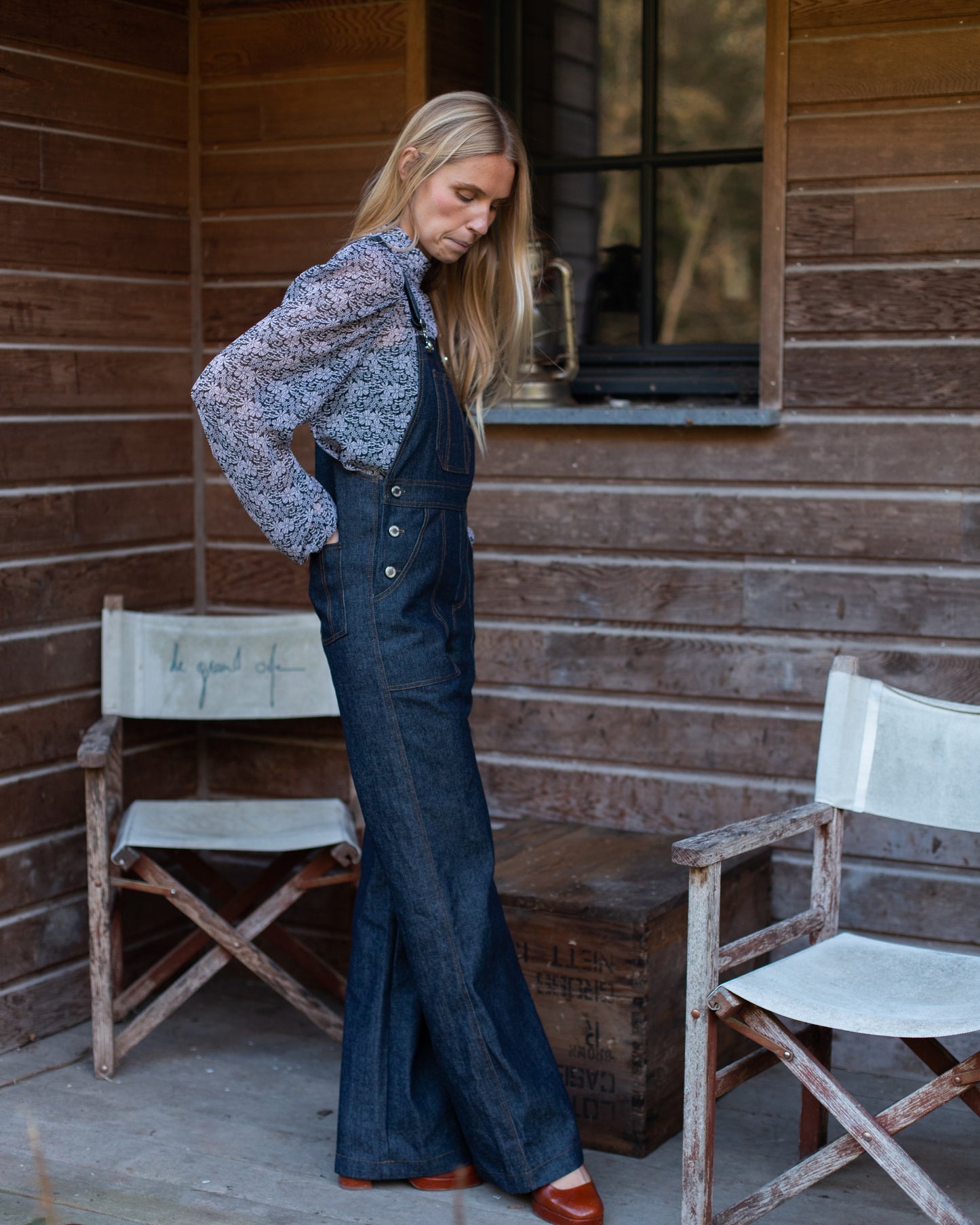 Salopette en denim brut modèle Dancing Queen portée par une mannequin, associée à une blouse fleurie.