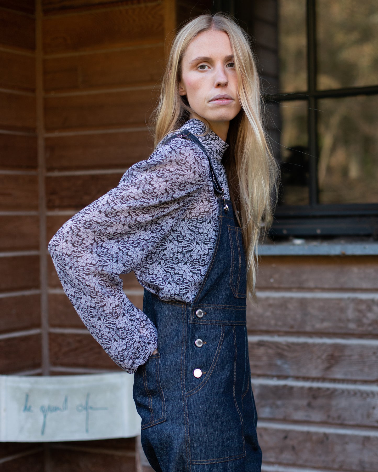 Salopette en denim brut modèle Dancing Queen portée par une mannequin, associée à une blouse fleurie.