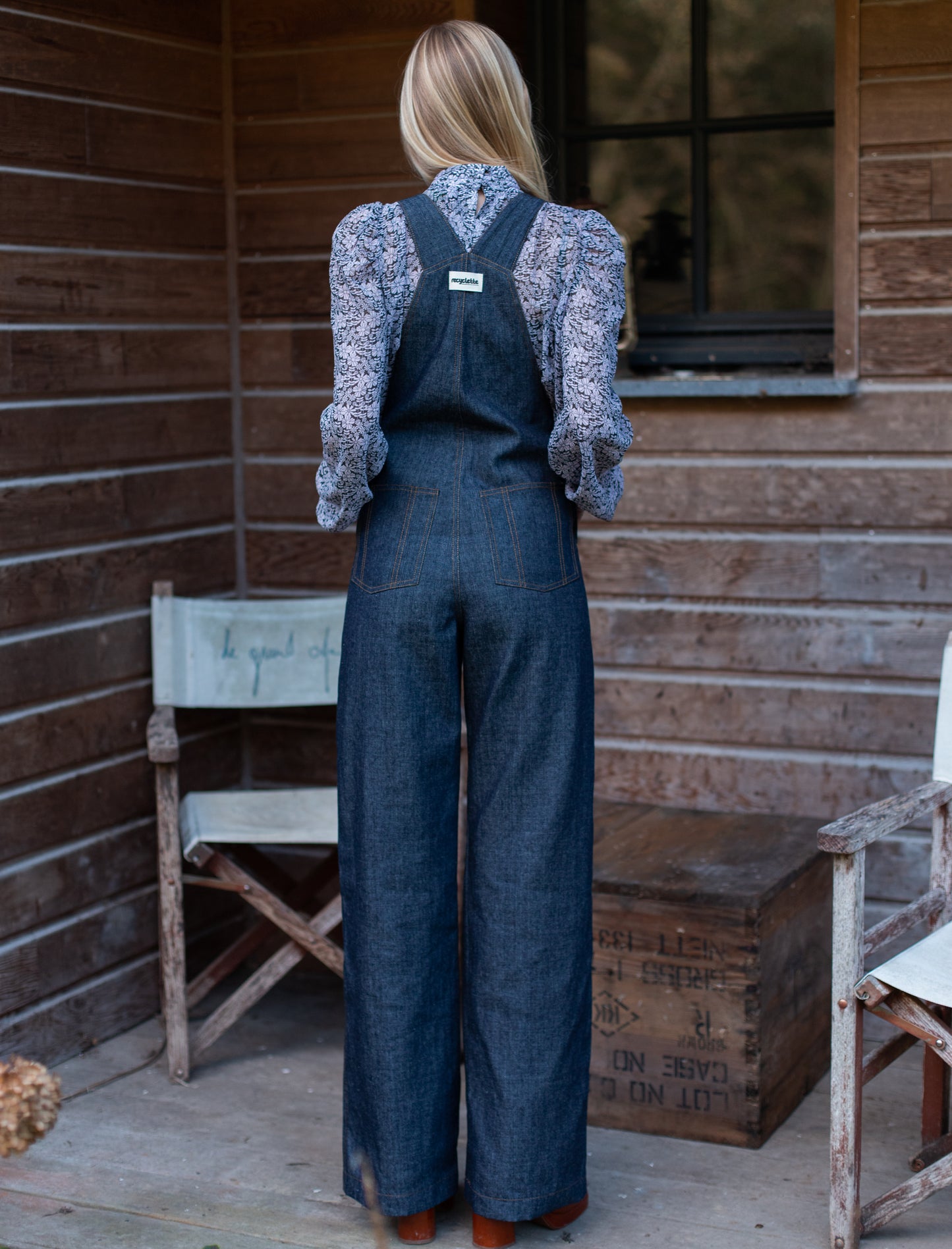 Salopette en denim brut modèle Dancing Queen portée par une mannequin, associée à une blouse fleurie.