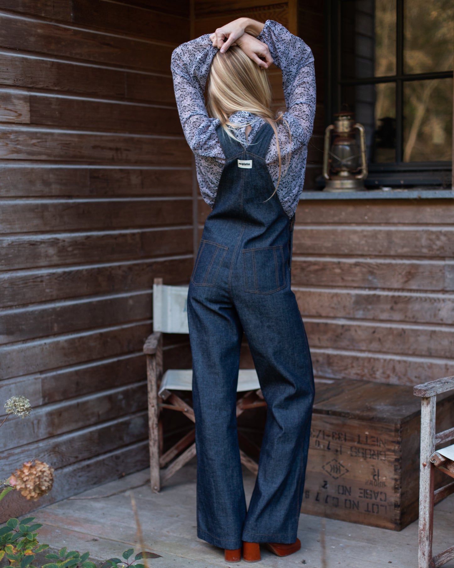 Salopette en denim brut modèle Dancing Queen portée par une mannequin, associée à une blouse fleurie.