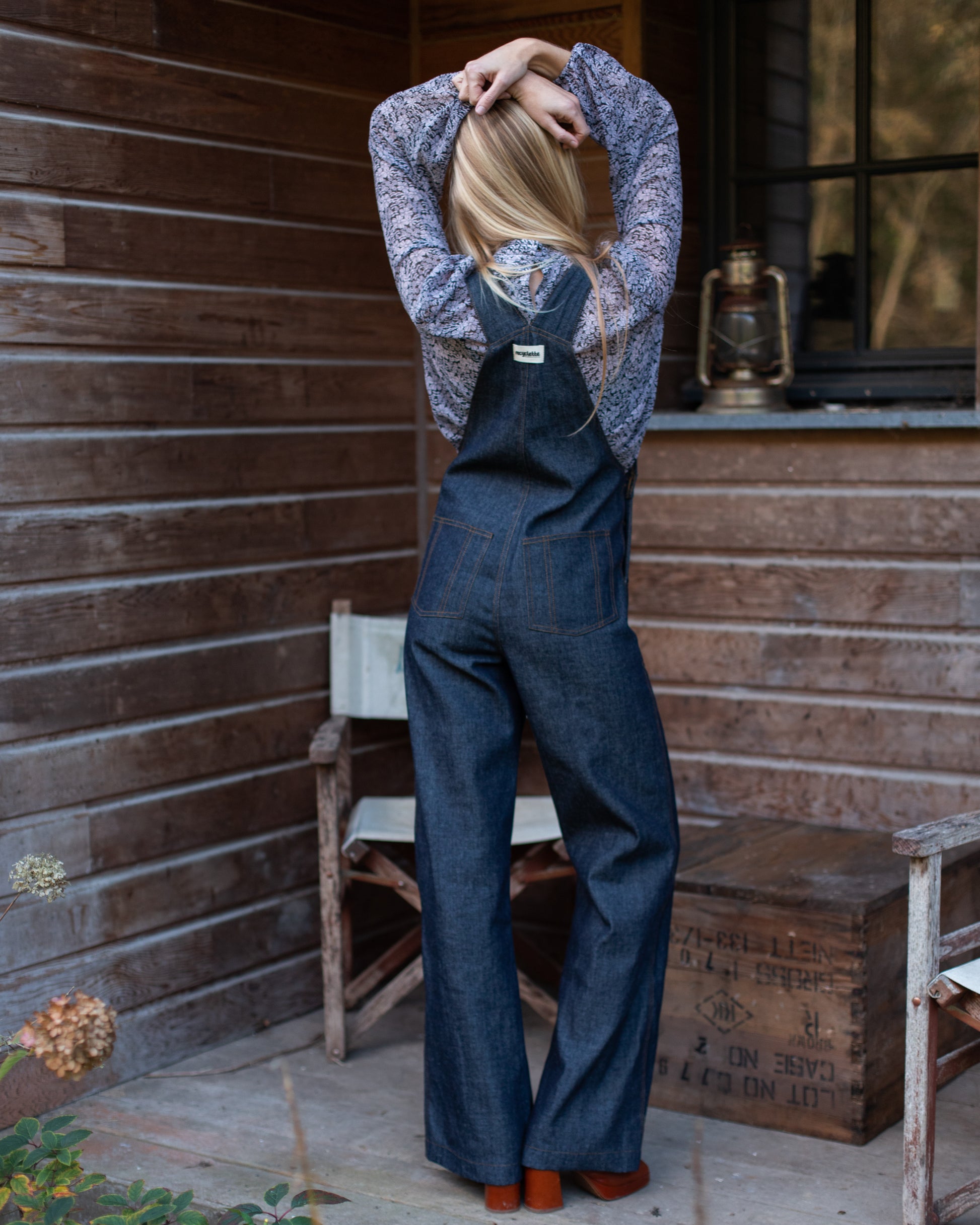 Salopette en denim brut modèle Dancing Queen portée par une mannequin, associée à une blouse fleurie.