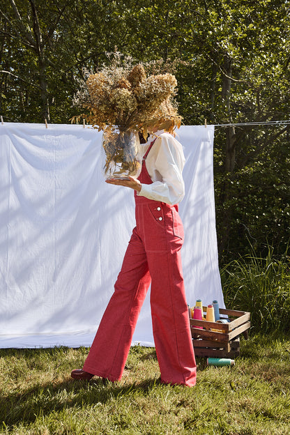 Salopette denim rouge dancing queen, accompagnée d'une blouse blanche et de talons.
