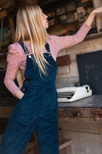 La salopette velours bleue, avec une blouse à carreaux.